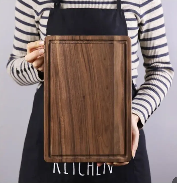 Lifestyle photo of a black rectangular walnut cutting board used for food preparation